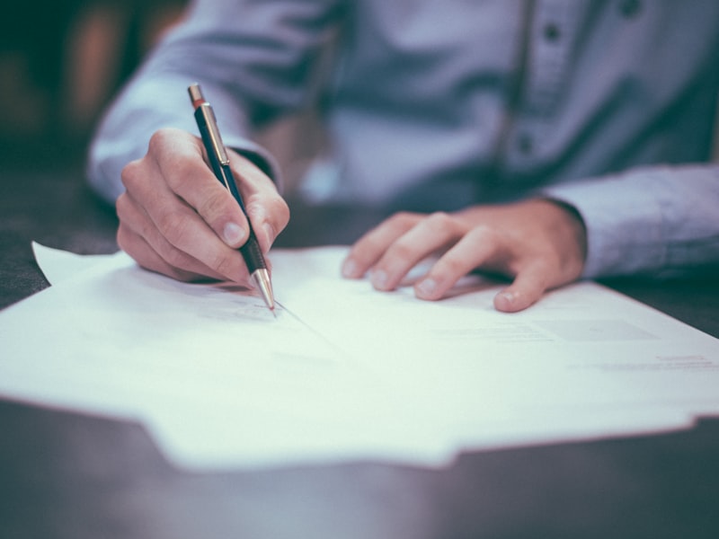 Persona che firma documenti contrattuali su una scrivania